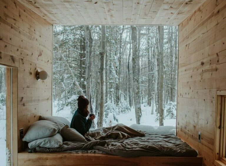 woman sitting on bed watching by the window during winter