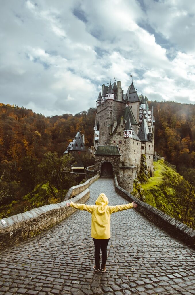 person wearing yellow hoodie standing in front of castle screenshot